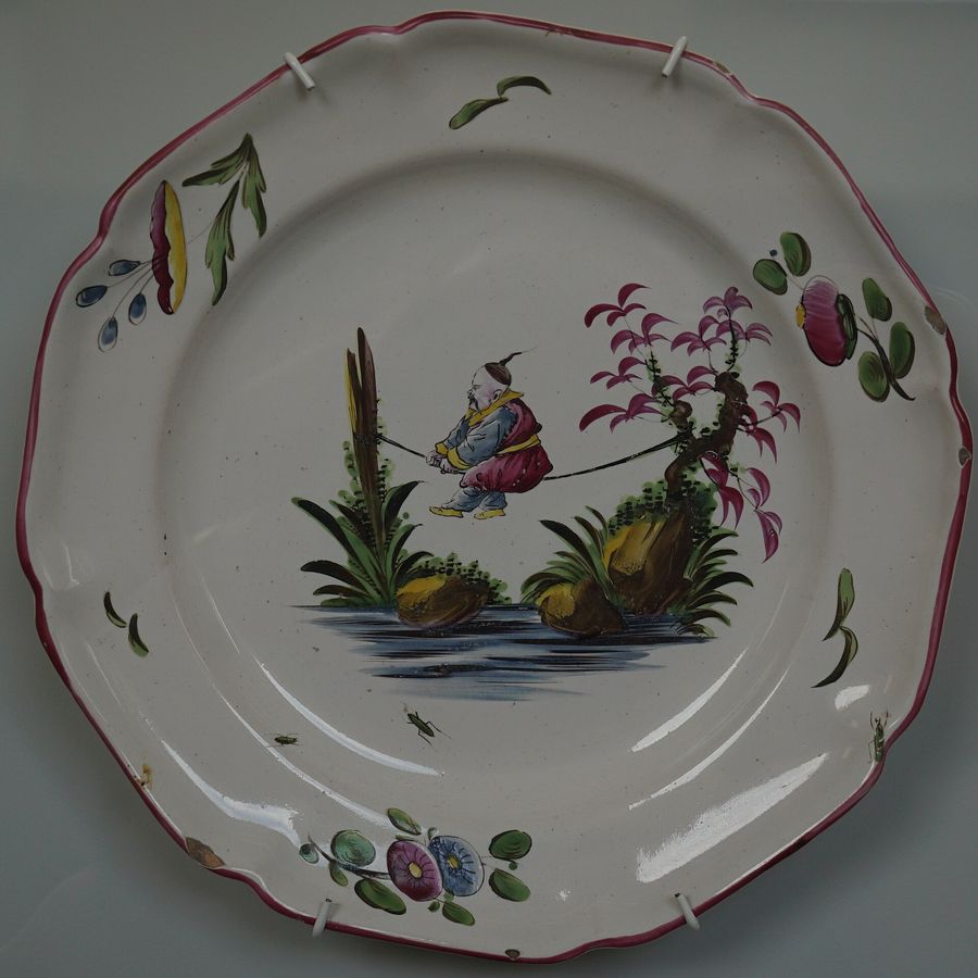 Assiette en faïence de Lunéville à bord contourné, personnage chinois et fleurs peints
